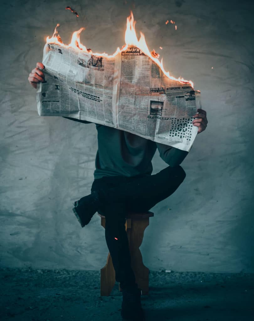 Homem com jornal pegando fogo