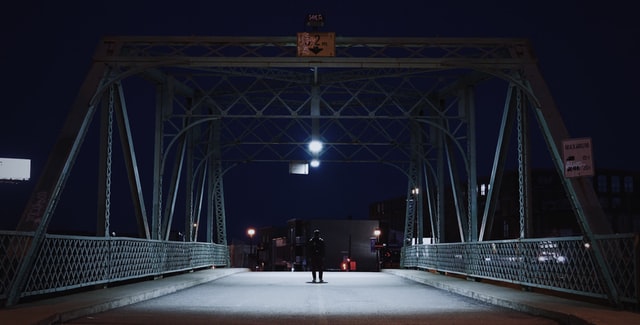 Homem parado sozinho numa ponte em meio ao isolamento social