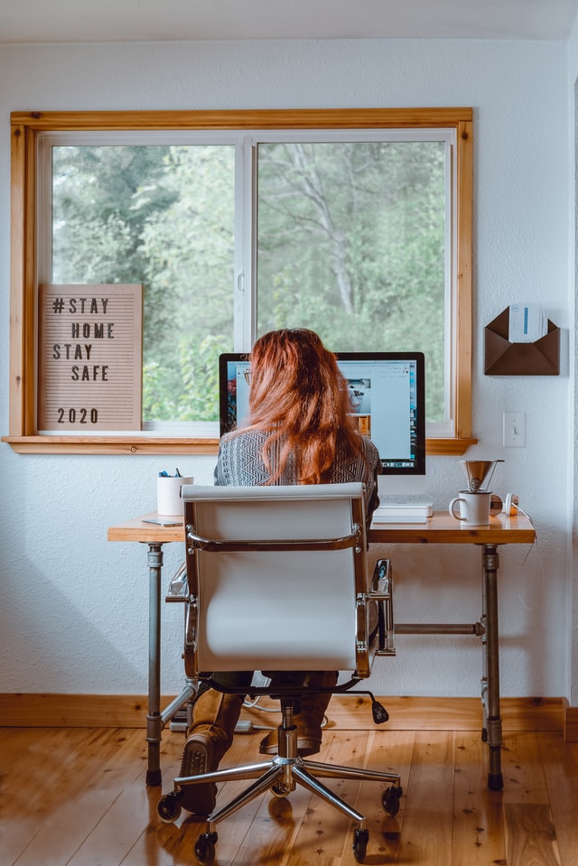 Mulher sentada em frente ao desktop, trabalhando em home office
